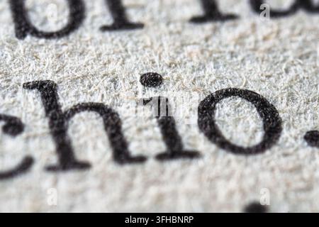 Close-up view capturing the intricate fibers of aged paper and the black ink of printed letters, highlighting the tactile texture and detailed typogra Stock Photo
