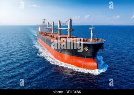 Close-up front view of a universal bulk carrier cargo ship traveling with high speed over blue ocean Stock Photo