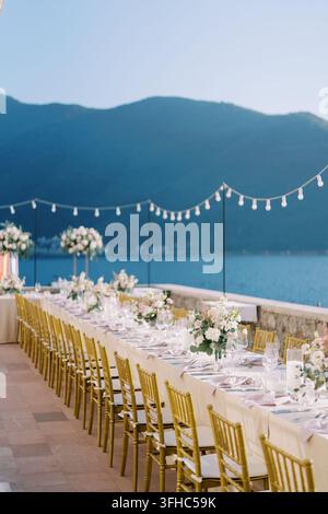 Elegant outdoor wedding dinner setup by the sea Stock Photo