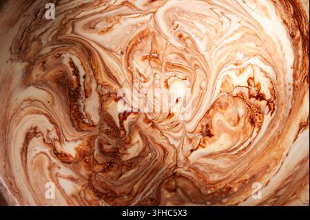 Abstract macro of swirling brown and cream liquid patterns, creating an organic marbled texture with flowing shapes Stock Photo