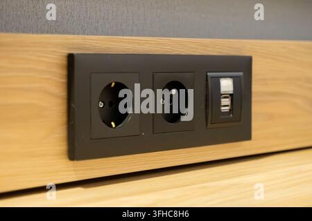 Modern black wall socket unit with integrated USB charging ports installed in a wooden surface, facilitating convenient power access and efficient dev Stock Photo