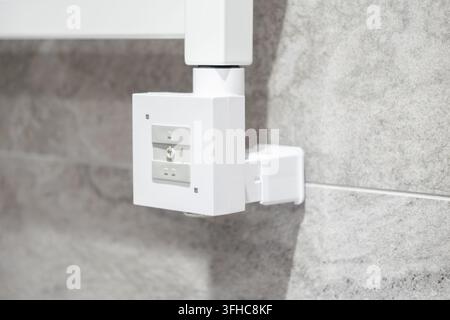 An electronic thermostat panel for a towel warmer mounted on textured tiled wall, representing smart residential temperature management and functional Stock Photo