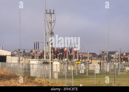 Industrial power transmission infrastructure features complex metal hardware and ceramic insulators, showcasing electricity grid technology within a m Stock Photo