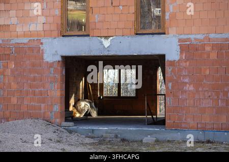 Exterior view of a new residential building under construction, revealing exposed red brick walls, an open entrance, and potential for future developm Stock Photo