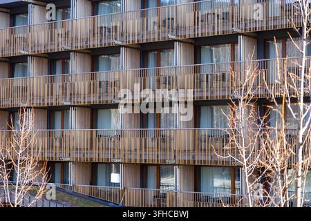 Szklarska Poreba, Poland - December 16, 2025: Close-up view of a modern building facade featuring wooden slat balconies and many windows, symbolizing Stock Photo