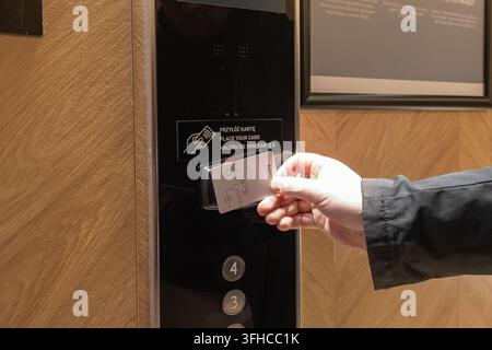 Szklarska Poreba, Poland - December 16, 2025: Guest's hand using a contactless key card to activate a smart elevator control panel, ensuring modern ho Stock Photo
