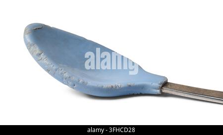 worn blue baby spoon isolated white background, chewed plastic coating and metal handle damaged feeding utensil in macro close-up view Stock Photo