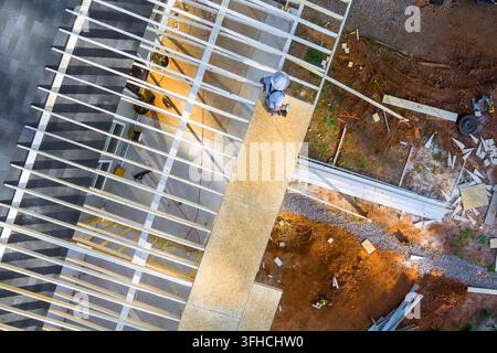 Construction roofing worker stands on wooden plywood at building site tools materials are scattered around. Stock Photo