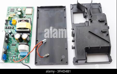 An electronic circuit board and its disassembled plastic housing are on a white surface Stock Photo