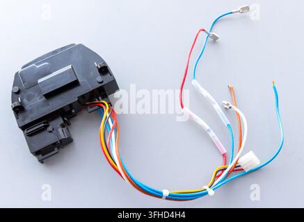 A black electronic component connects to a vibrant bundle of electrical wires Stock Photo