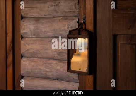 Vintage wall mirror mounted on a rustic wooden log wall, featuring an aged frame and reflective glass. Warm golden light reflected in the mirror. Stock Photo