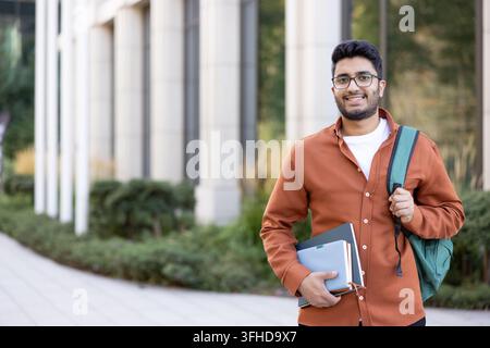 Happy Indian student with backpack and books, university education and academic success. Stock Photo