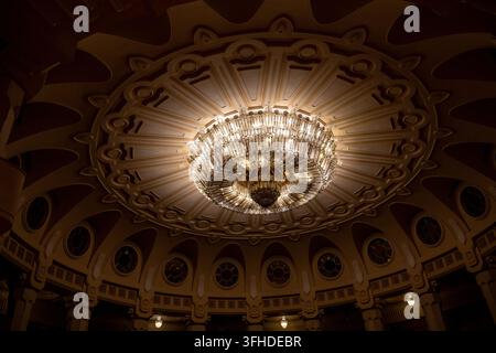 Low-angle view of a glowing chandelier and patterned dome inside the Palace of Parliament in Bucharest, Romania. Stock Photo