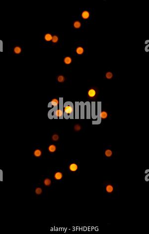 Warm orange bokeh lights on black background for abstract holiday and night photography Stock Photo