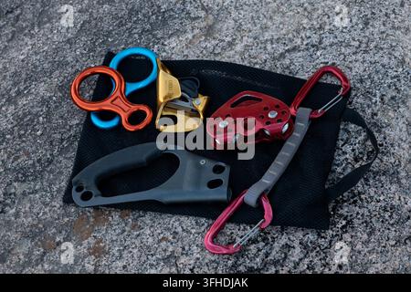 Various colorful climbing and caving equipment resting on a dark rock background Stock Photo