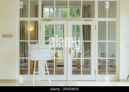 elegant indoor wedding reception area with glass doors and wooden chairs, welcoming guests to a formal ceremony front view  Stock Photo
