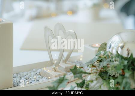 Close-up of heart-shaped decorations with white pebbles and greenery in an indoor setting, possibly a home or event space, creating a romantic and Stock Photo