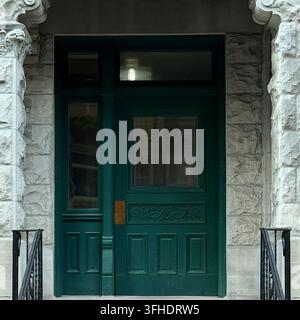 Green door within a recessed entrance framed by rough stone and carved ornament. Stock Photo