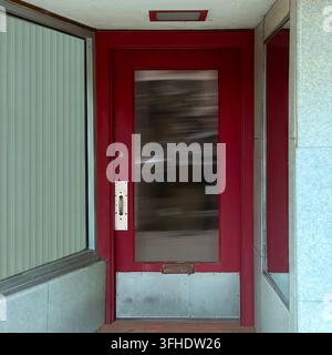 Storefront red door with a tall reflective glass panel and silver kick plate. Stock Photo