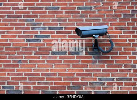 Security camera is mounted on a textured brick wall, ensuring protection and monitoring Stock Photo