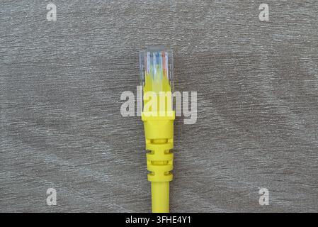 Macro shot focusing on a yellow RJ45 network cable connector and plastic latch, emphasizing network security, IT hardware, and high-speed data connect Stock Photo