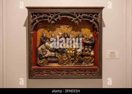 Bucarest, Romania - 6 Nov 25: Gilded carved religious relief showing figures around a bed, displayed at the Romanian National Museum of Art in Buchare Stock Photo