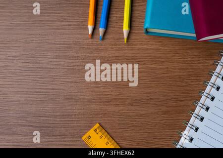Flat lay of office stationery with colored pencils, notebooks and ruler with copy space on a wooden desk. Back to school, education, workplace Stock Photo