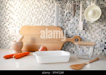 Kitchen utensils hanging on rail track near mosaic wall background.  Stock Photo