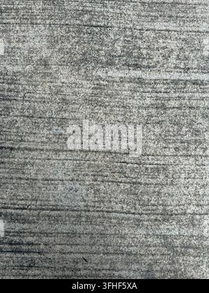 Close-up of rough grey concrete pavement with horizontal grooves, scratches and natural weathering. Stock Photo