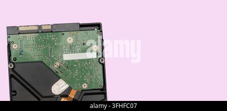 A hard drive circuit board is placed on a pink background. This board shows various electronic parts and connections clearly. The focus is on the tech Stock Photo