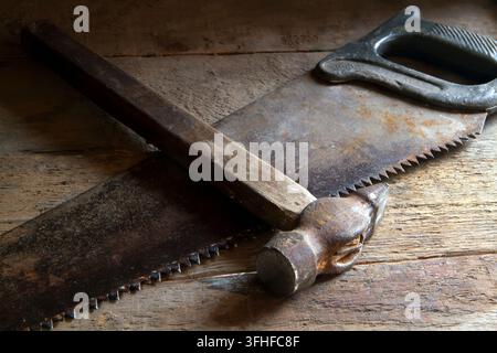 Old hacksaw and hammer on the boards. Old working tools. Stock Photo