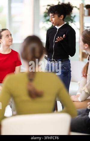 African American girl speaks to a group at a school class, explaining her point of view. Schoolgirl practicing speaking in an acting club with the res Stock Photo