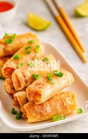 Fried spring rolls served with lime and sauce on a white plate Stock Photo