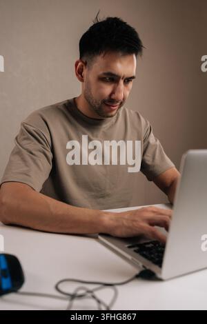 Vertical portrait of freelancer male concentrating on work, typing on a laptop computer, engaged in remote work, freelancing, or online education from Stock Photo