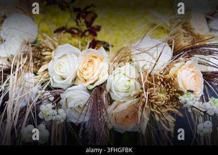 Bouquet of white and yellow roses, dried grasses, small berries, rich texture, natural rustic style, elegant composition, soft lighting, warm earthy c Stock Photo