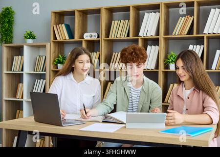 Students collaborating on school project with laptop and tablet in modern library Stock Photo