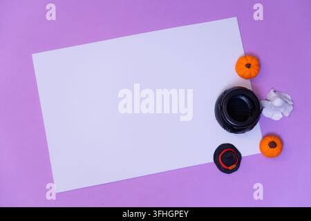 A top-down view of a rectangular white space on a purple background featuring a cauldron surrounded by pumpkins, a witch hat, and a ghost. Stock Photo