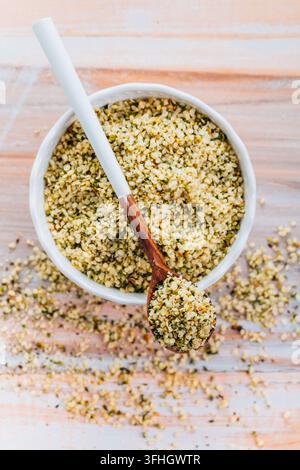 Nutritious hemp seeds in a white ceramic bowl with a wooden spoon Stock Photo