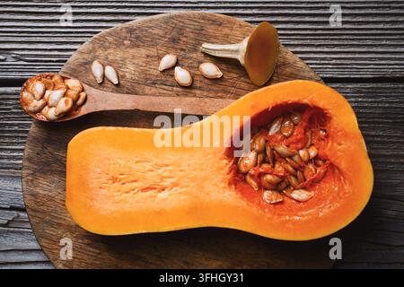 Butternut squash on wooden board with seeds and spoon in rustic setting. Autumn cooking preparation with pumpkin and organic ingredients Stock Photo