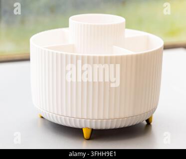 A white ribbed organizer with gold feet sits on a grey table Stock Photo