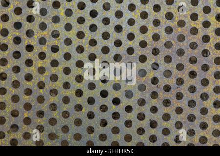 Rusty metal surface with uniform circular perforations Stock Photo