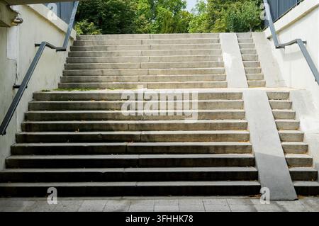 Concrete outdoor staircase with wheelchair access ramps leading to a park Stock Photo