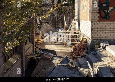 Scattered building materials lie near a residential house undergoing exterior renovation, reflecting home improvement projects and labor intensive sit Stock Photo