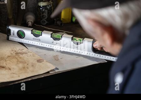 A focused tradesman examines a metal bubble level on a project surface, emphasizing attention to detail and accurate measurements during a traditional Stock Photo