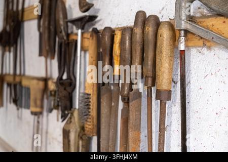 A collection of antique rasps and iron tools rests on a rustic garage rack, reflecting skilled trade professions, DIY hardware restoration, carpentry Stock Photo