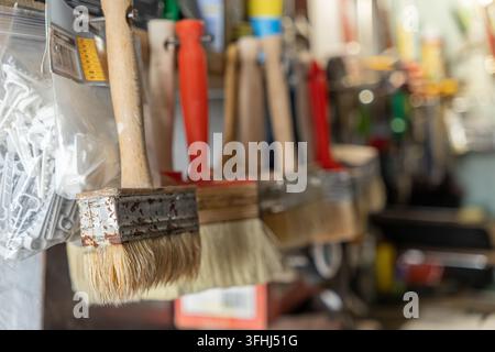 Professional paint brushes hang suspended on a retail rack, illustrating the essential tools required for painting projects, home repairs, or construc Stock Photo