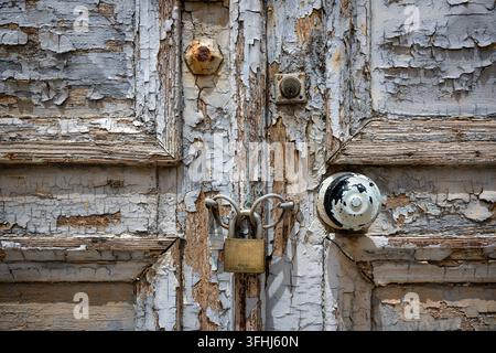 Old Padlocked Door with Peeling Paint and Weathered Wood Stock Photo