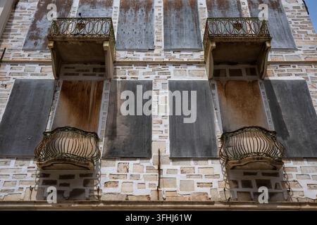 Weathered balconies and shuttered windows on old building, Syros, Greece Stock Photo