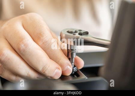 Close-up of a person holding a socket tool while assembling heavy machinery, where the focus on construction highlights technical expertise, manual cr Stock Photo