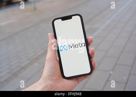 Meta corporation logo displayed on smartphone with city sidewalk backgorund Stock Photo